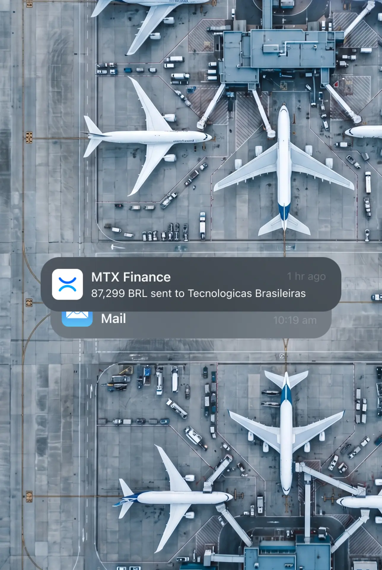 Aerial top-down view of airplanes parked at an airport terminal with an MTX Finance notification
