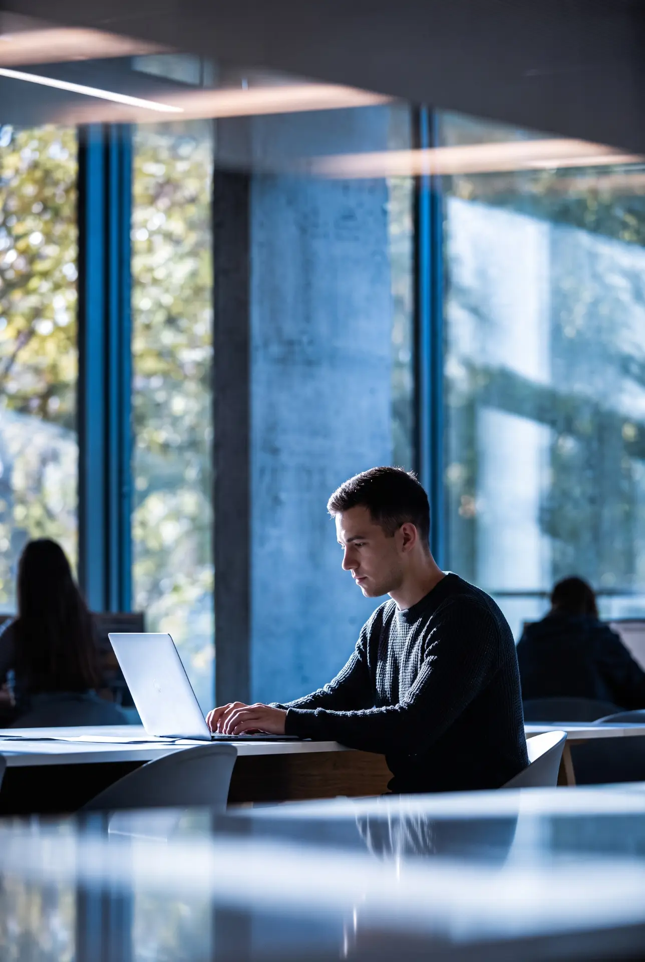 A man working on a laptop in a modern blue-toned office