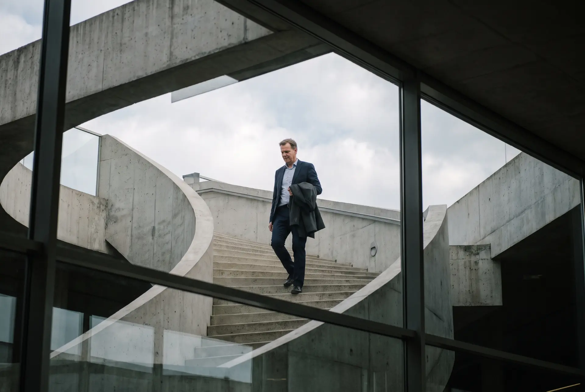 Businessman walking down a spiral concrete staircase of a modern building
