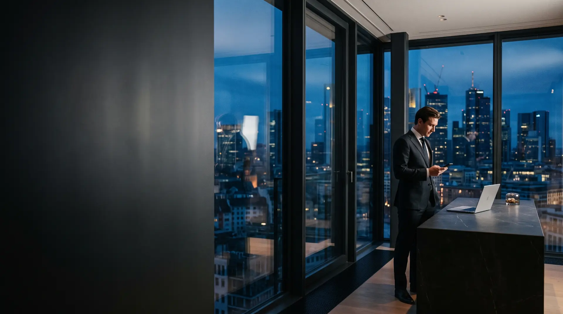 A man working at a laptop in a high-rise office at night