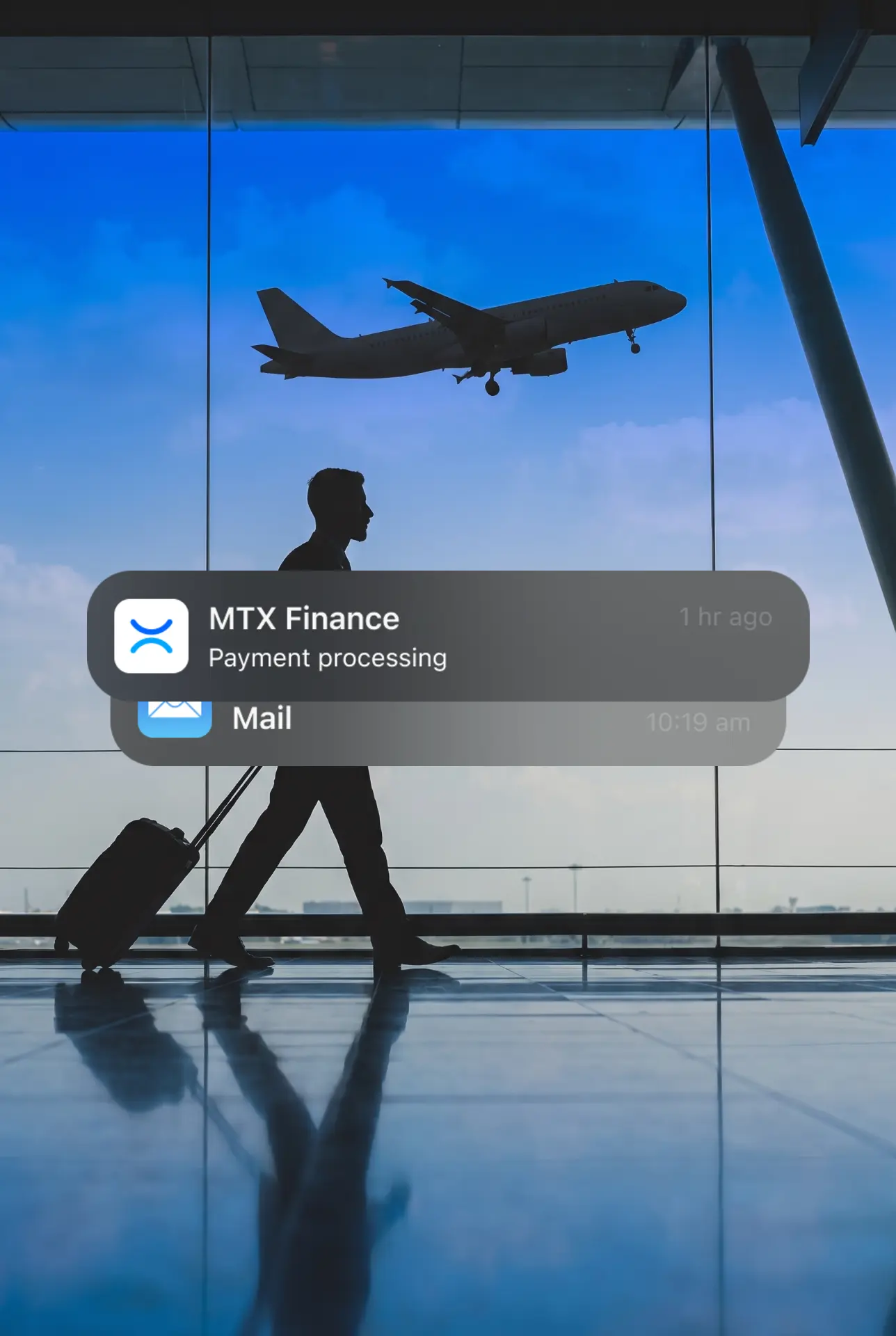 A suited traveller walking through an airport terminal with an MTX Finance notification