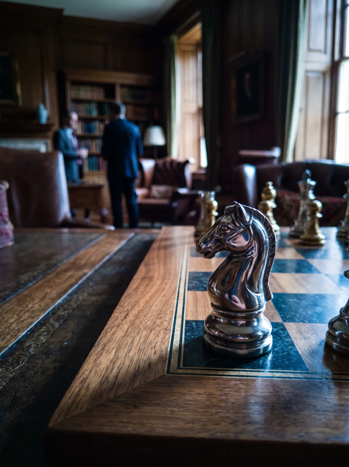 Silver knight on a chessboard in a dark wood library